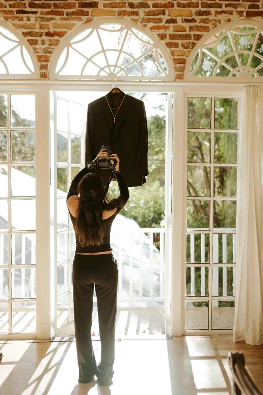 Kaylee photographing the groom's suit in a light-filled arched room